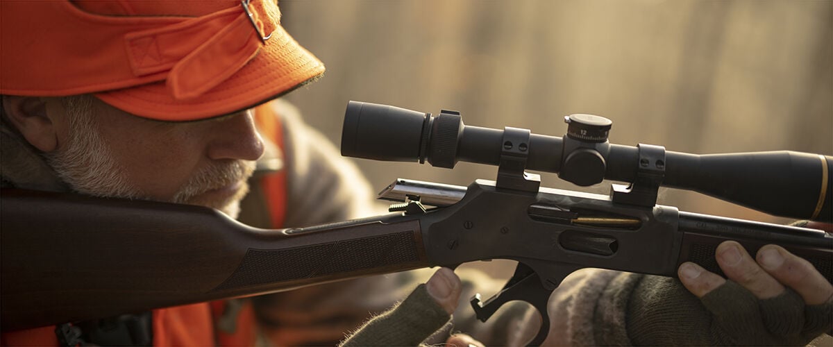 Man looking through scope of rifle